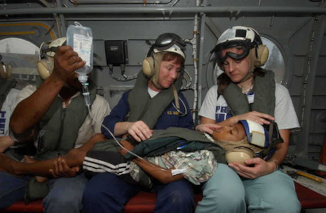 U.S. Navy Nurse Cmdr. Karen McDonald (center) and a nurse from the organization Project HOPE (right) comfort a young boy suffering from a perforated appendix aboard a U.S. helicopter in Sumatra, Indonesia, on Feb. 6, 2005. The boy and his father (left) are being transported to the hospital ship USNS Mercy (T-AH 19) for medical attention. Mercy is currently off the coast of Banda Aceh, Sumatra, Indonesia, to provide medical assistance and disaster relief to the people of Indonesia affected by the devastating tsunami that hit Southeast Asia on Dec. 26, 2004. McDonald is the Mercy's assistant director of Nursing. 