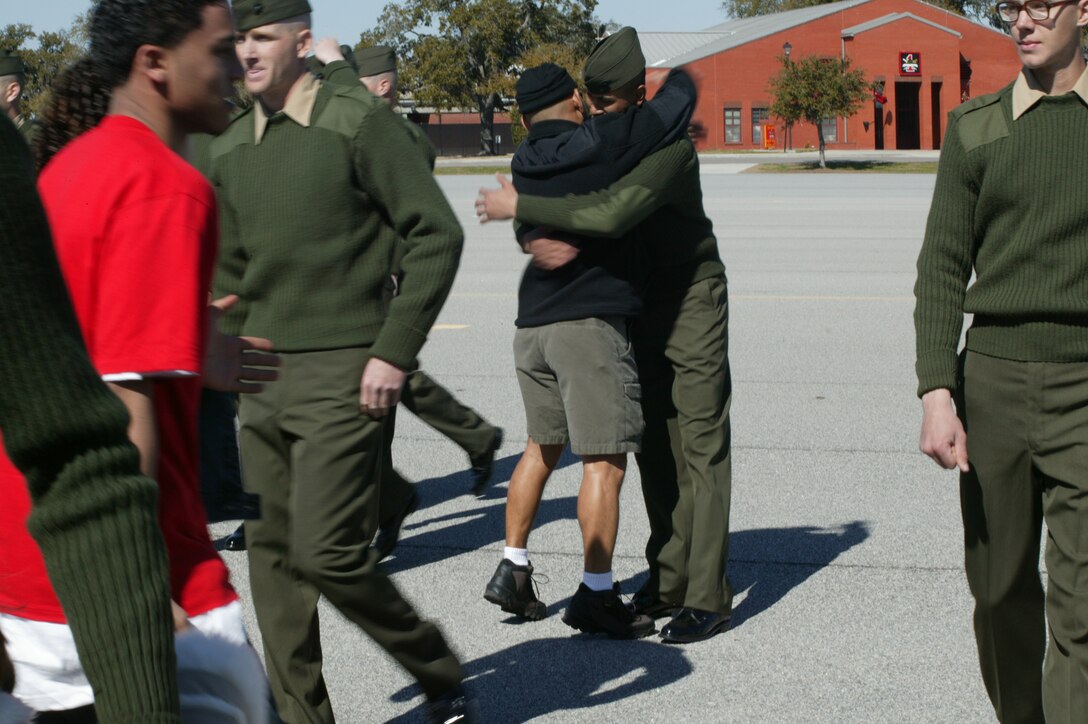 As families rush to see their new Marines, Private First Class Joseph Garrido, Delta Co., 1st RTBn., and his father, Joseph Garrido hug each other for the first time in 13 week following the Emblem Ceremony at the Peatross Parade Deck Feb. 10.