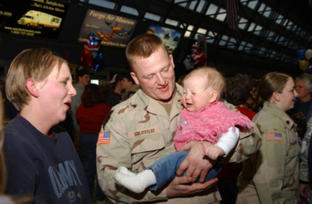 Army Sgt. Robb H. Schlotfeldt holds his daughter for the first time in several months while his wife looks on at Hector International Airport, Fargo, N.D., on Feb. 8, 2005. Schlotfeldt, of the 141st Engineer Combat Battalion, has just returned from a one-year deployment to Iraq. 