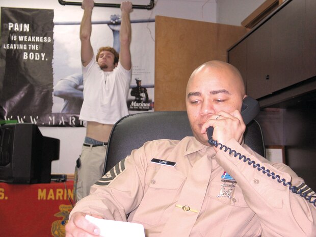 Gunnery Sgt. Terry D. Love, SNCOIC, RSS Flint, talks on the phone at his office Feb. 14, 05 while Poolee Josh R. Romanetto, 18, goes for some pull ups. Romanetto leaves for boot camp July 5, 06. Love was an infantryman and also attained Centurion status during his first tour of recruiting duty in RS Lansing a few years ago. He won the MFL's SNCOIC position for 2005. He is hoping to some day become an ARI or an RI.
