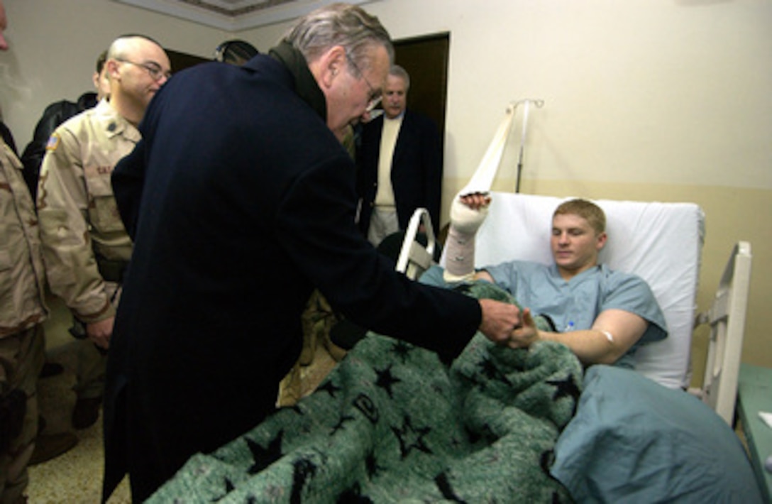 Secretary of Defense Donald H. Rumsfeld awards Army Sgt. Sean Ferguson his second Purple Heart at the Combat Surgical Hospital in Mosul, Iraq, on Feb. 11, 2005. Rumsfeld made an unannounced visit to Iraq to meet with the senior leadership, key government officials and talk to the troops. 
