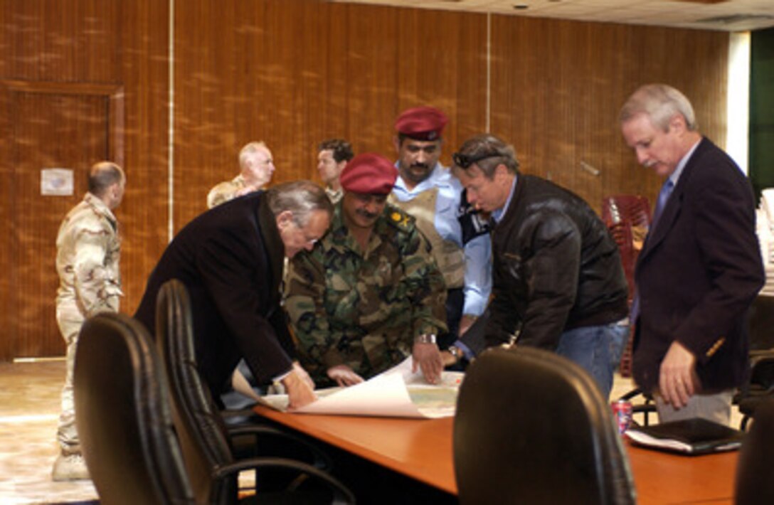 Secretary of Defense Donald H. Rumsfeld (left) looks over an Iraqi map as he meets with members of the Iraqi Special Police Commando unit in Baghdad, Iraq, on Feb. 11, 2005. Rumsfeld made an unannounced visit to Iraq to meet with the senior leadership, key government officials and talk to the troops. 