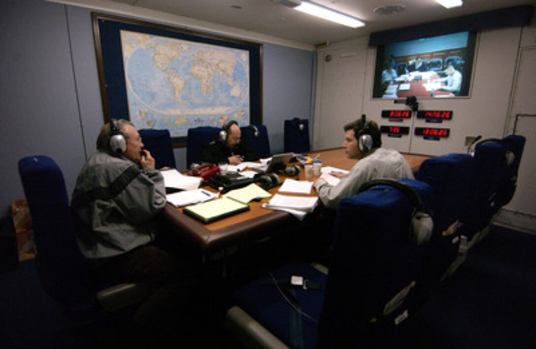 Secretary of Defense Donald H. Rumsfeld (left) speaks with senior staff members in the Pentagon via a secure teleconference link on board an E-4B National Airborne Operations Center aircraft en route to Washington, D.C., from Munich, Germany, on Feb. 12, 2005. 