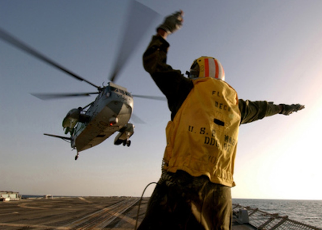 Petty Officer 2nd Class Itro Duncan signals the pilot of an H-3 Sea King helicopter that it is clear to move away from the flight deck of the USS Mason (DDG 87) as the ship operates in the Persian Gulf on Feb. 5, 2005. The Arleigh Burke class destroyer is conducting operations in the Gulf as a part of Destroyer Squadron 26 and the USS Harry S. Truman (CVN 75) Carrier Strike Group. The Sea King, from Helicopter Combat Support Squadron 2, and the USS Mason are both deployed from Norfolk, Va. 