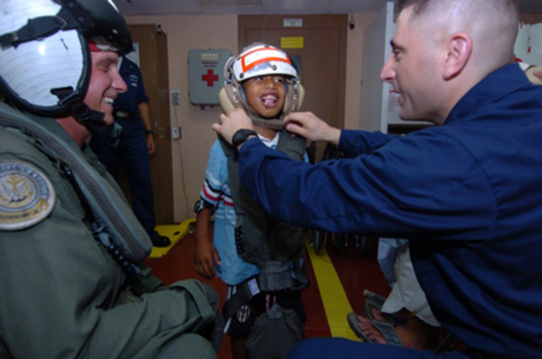 Chief Petty Officer Patrick Nordulli (right) and Petty Officer 2nd Class Jeffery Moore (left) prepare discharged Indonesian patient Wahyu Firmandao for a helicopter flight ashore by securing the chin strap on his cranial helmet, onboard the Navy hospital ship USNS Mercy (T-AH 19), on Feb. 14, 2005. Mercy is operating off the coast of Banda Aceh, Sumatra, Indonesia, to provide medical assistance and disaster relief to the people of Indonesia affected by the devastating tsunami that hit Southeast Asia on Dec. 26, 2004. Firmandao was the first Indonesian patient treated onboard Mercy for a perforated appendix. 