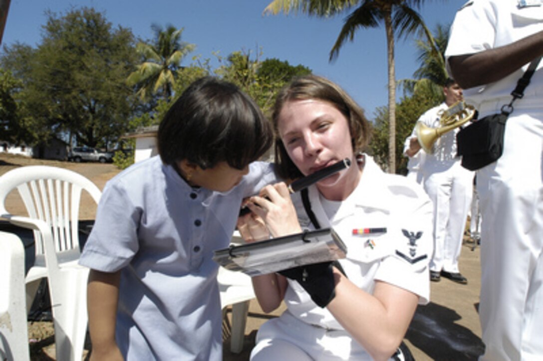 Navy Musician Petty Officer 3rd Class Amanda Leslie plays the flute while a student from the Saint Francis Xavier School for Children with Special Needs in Goa, India, tries to get into the act on Feb. 16, 2005. Sailors from the amphibious command ship USS Blue Ridge (LCC 19) and the embarked Seventh Fleet staff participated in the project by refurbishing part of the school's multi-purpose facility during the ship's routine port visit. Leslie is assigned to the U.S. Seventh Fleet Band. 
