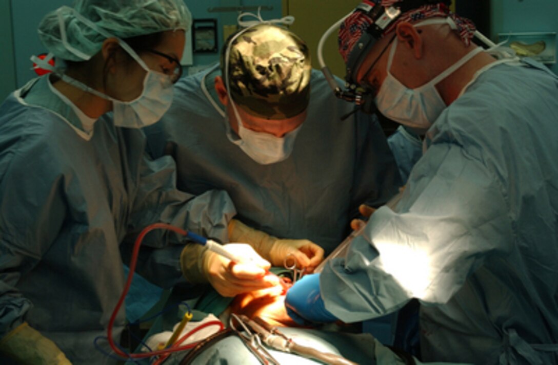 Navy Lt. Joyce Yang (left) DDS, Lt. Cmdr. Terence Johnson (center) M.D., and Cmdr. Kurt Hummeldorf (right) DDS, perform oral surgery on an Indonesian man to remove a cyst from his mouth onboard the hospital ship USNS Mercy (T-AH 19) on Feb. 18 2005. Mercy is operating off the coast of Banda Aceh, Indonesia, providing medical assistance and disaster relief to those affected by the Dec. 26, 2004, Indian Ocean tsunami. 