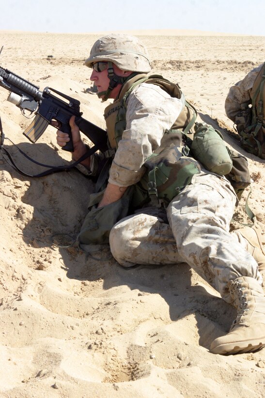 UDAIRI RANGE, Kuwait (Feb. 18, 2005) -- Cpl. Philip B. Olmstead, 21, an infantryman with A Co., Battalion Landing Team 1/1, and a native of Mesa, Ariz., takes cover behind a berm, and reaches for a grenade during a squad live-fire exercise. BLT 1/1, attached to the 15th Marine Expeditionary Unit (Special Operations Capable), is training in Kuwait to maintain their combat readiness.