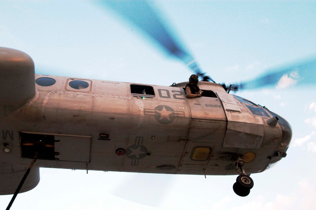 UDAIRI RANGE, Kuwait -- (Feb. 18, 2005) - A CH-46E crew chief with Marine Medium Helicopter Squadron 165 (REIN) watches the Helicopter Suspension Team hook a block of concrete to the aircraft durng external training here. Crew chiefs talk directly to the pilot ensureing they hover at the correct altitude when the load is being connected. (Official USMC Photo by Gunnery Sgt. Robert Knoll)