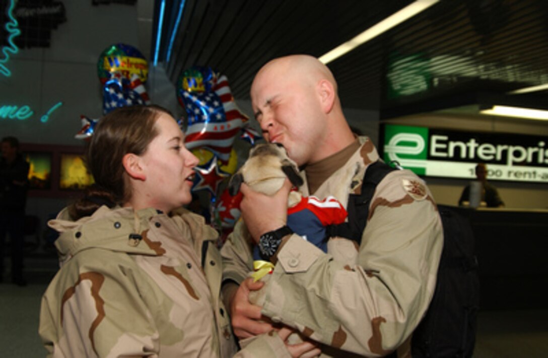 National Guard Spc. Amy Egbert can only watch as her husband Sgt. Dallas Egbert (right) gets a big kiss from their dog as they arrive at Hector International Airport, in Fargo, N.D., on Feb. 16, 2005. The Egberts are returning home after a one-year deployment to Iraq with the 141st Engineer Combat Battalion. 