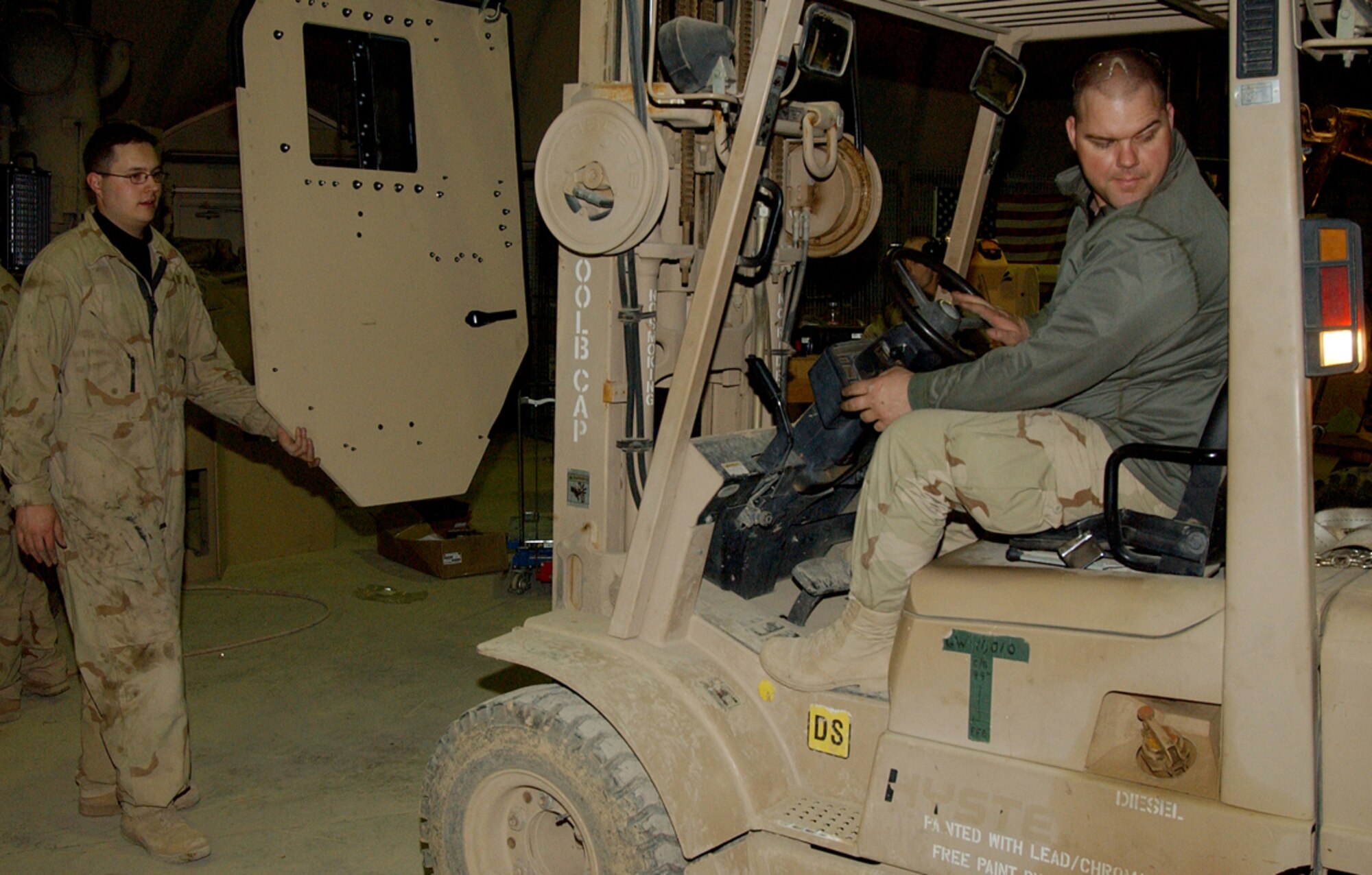 BALAD AIR BASE, Iraq -- Senior Airman Matthew Brock steadies an armored door as Tech. Sgt. Robert Riley moves it to an awaiting vehicle.  Airman Brock is a 732nd Expeditionary Logistics Readiness Squadron vehicle maintainer deployed from Royal Air Force Fairfield, England, and Sergeant Riley is a 732nd ELRS vehicle maintainer deployed from Misawa Air Base, Japan.  