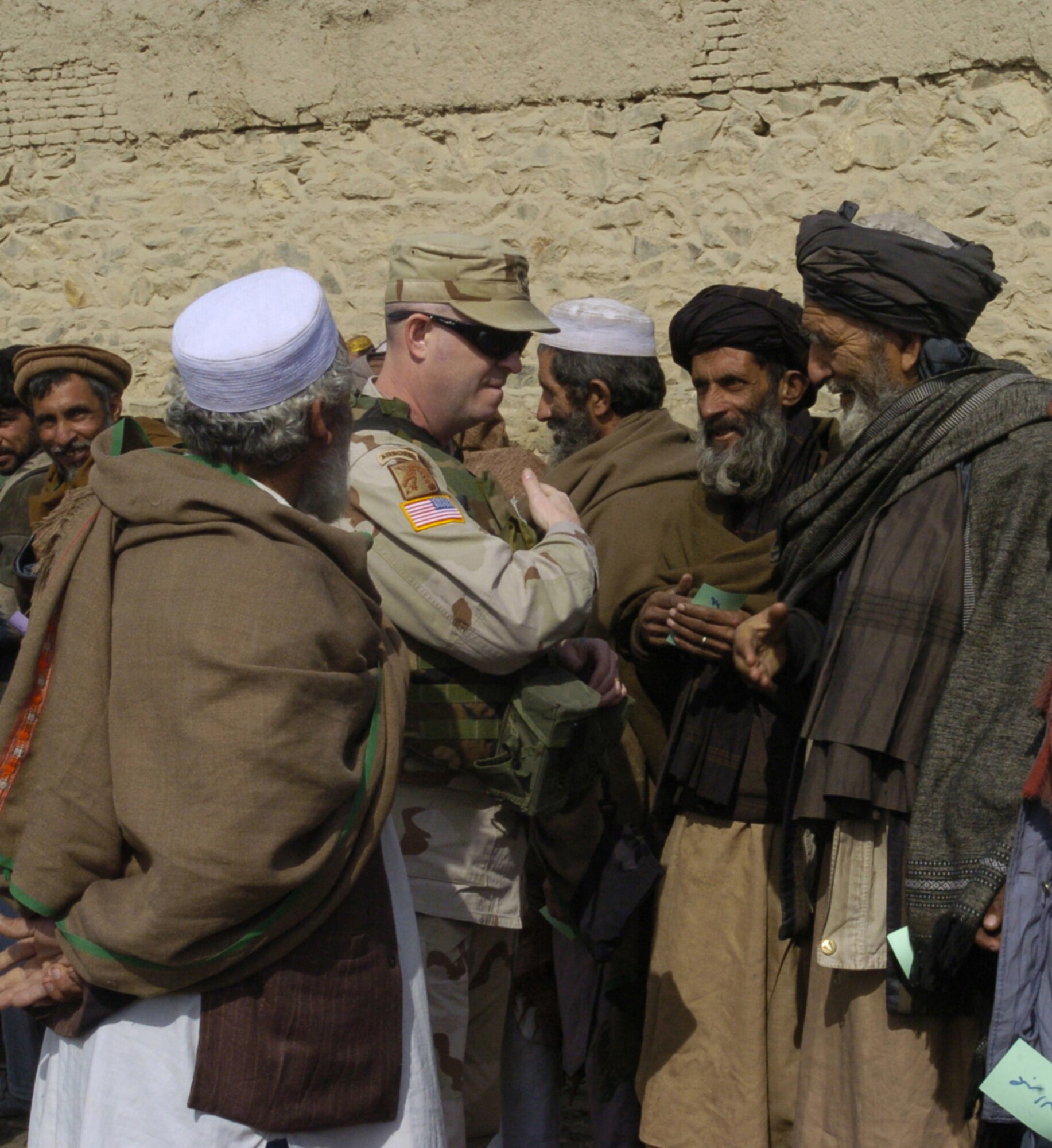 KABUL, Afghanistan -- Army Sgt. 1st Class Darren Heusel greets Afghans before handing out supplies during a humanitarian visit here Feb. 22.  He and other Soldiers of the 105th Mobile Public Affairs Detachment collected more than 30 boxes of supplies from Oklahoma and Kansas, including toiletries, clothing, food, toys, school supplies and blankets for Afghan families.  (U.S. Air Force photo by Senior Airman Catharine Schmidt)