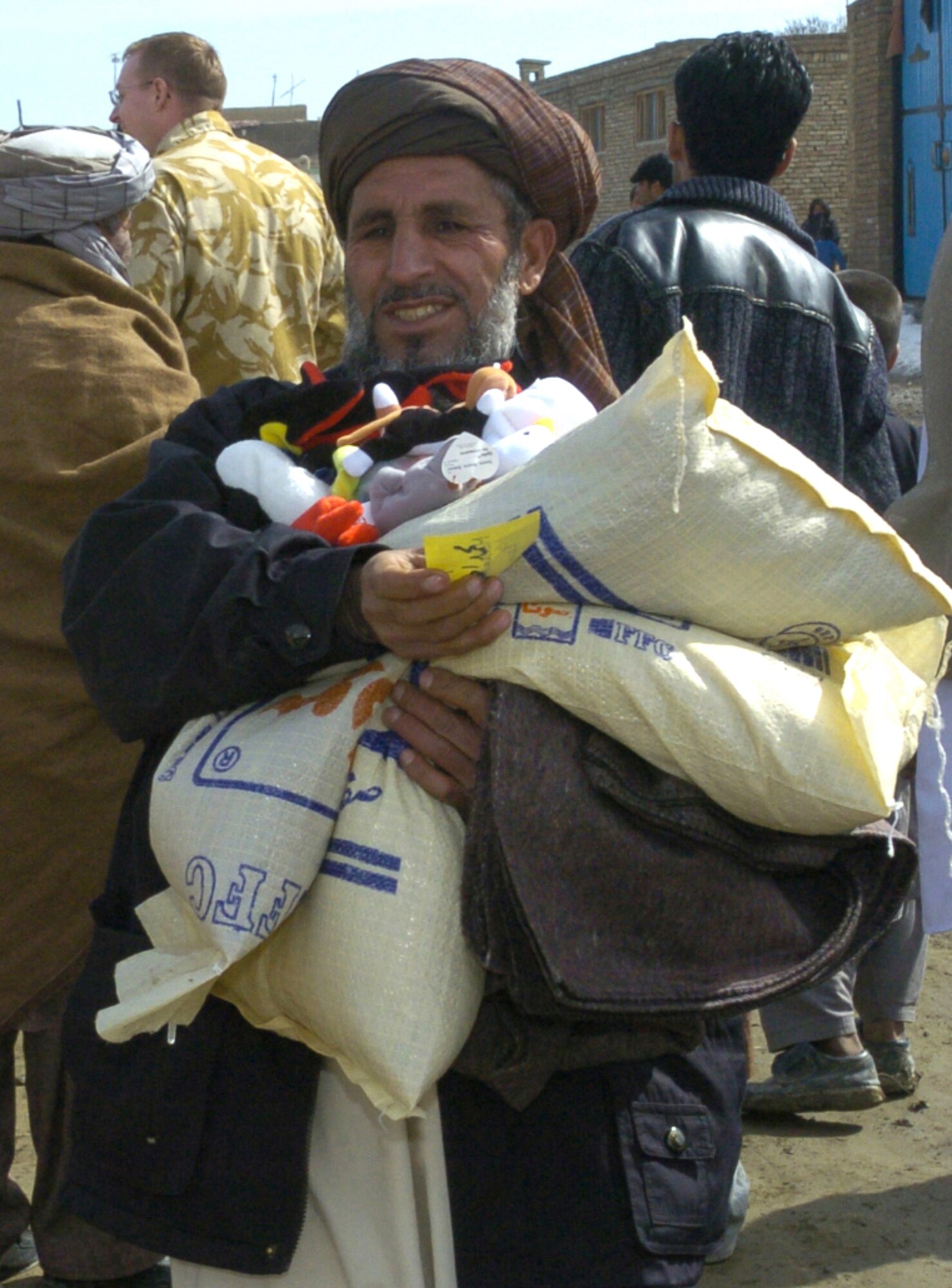 KABUL, Afghanistan -- An Afghan carries toys and beans he just received from coalition forces during a humanitarian visit here Feb. 22.  Soldiers of the 105th Mobile Public Affairs Detachment collected more than 30 boxes of supplies from Oklahoma and Kansas, including toiletries, clothing, food, toys, school supplies and blankets for Afghan families.  (U.S. Air Force photo by Senior Airman Catharine Schmidt)