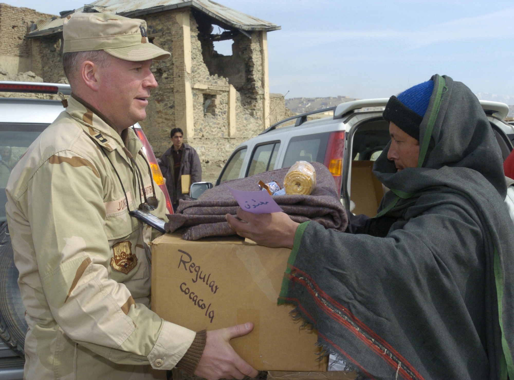 KABUL, Afghanistan -- Capt. Scott Jones hands a box of donated items to an Afghan during a humanitarian visit here Feb. 22.  Soldiers of the 105th Mobile Public Affairs Detachment collected more than 30 boxes of supplies from Oklahoma and Kansas, including toiletries, clothing, food, toys, school supplies and blankets for Afghan families.  Captain Jones is assigned to Combined Forces Command-Afghanistan.  (U.S. Air Force photo by Senior Airman Catharine Schmidt)