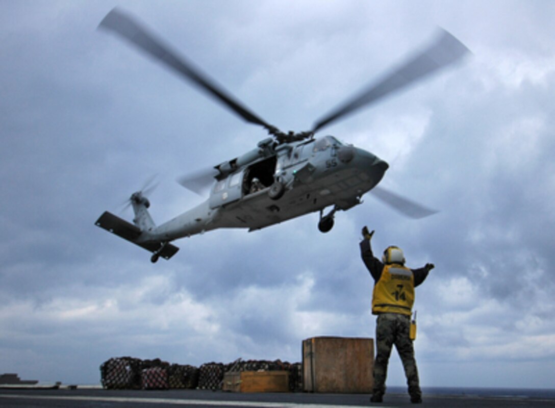 Airman Matt Newell directs the pilot of MH-60S Knighthawk helicopter after dropping off a pallet of cargo to the flight deck of USS Kitty Hawk (CV 63) during a vertical replenishment with the USNS Kiska (T-AE 35) on Feb. 22, 2005. The aircraft carrier Kitty Hawk is receiving supplies from the ammunition ship Kiska as the two ships steam at sea. Newell is from Flippin, Ark. 