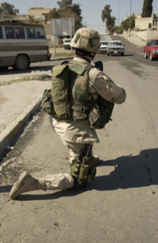 Army Cpl. Torria Maynard kneels in the street to face on-coming traffic while providing security for the rest of his company in Mosul, Iraq, on Feb. 24, 2005. Maynard and other soldiers of Headquarters and Headquarters Company, 1-24 Infantry, 1st Brigade, Stryker Brigade Combat Team, 25th Infantry Division, Fort Lewis, Wash., are looking for insurgents in Mosul. 