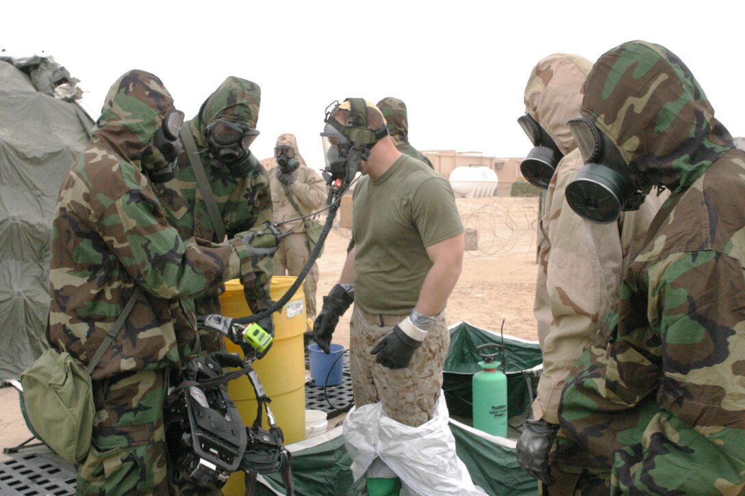 Lance Cpl. Wayne E. Barba, 34, a Nuclear Biological and Chemical Defense specialist with Marine Medium Helicopter Squadron 165 (REIN), and a native of Quincy, Mass., is undressed by other Marines and Sailors after working in contaminated environment. The 15th Marine Expeditionary Unit (Special Operations Capable) is training in Kuwait to sharpen their skills as a Marine Air Ground Task Force.