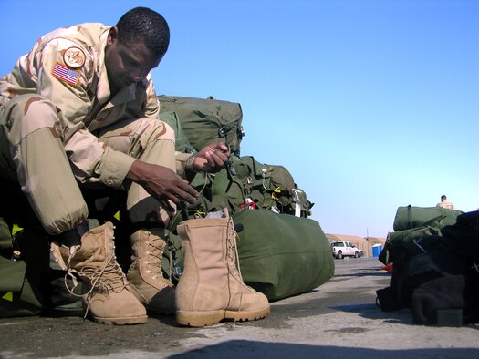 MANAS AIR BASE, Kyrgyzstan -- Army Sgt. 1st Class Harold Washington sits atop a mound of duffle bags while changing his boots.  More than 1,500 transient troops made their way through the base Feb 22 to 26, pushing the base to a 190 percent occupancy rate.  Officials with the 376th Expeditionary Services Squadron shut down the base fitness facility as well as various recreational areas to house the visitors.  (U.S. Air Force photo by Staff Sgt. J. Russell Martin)