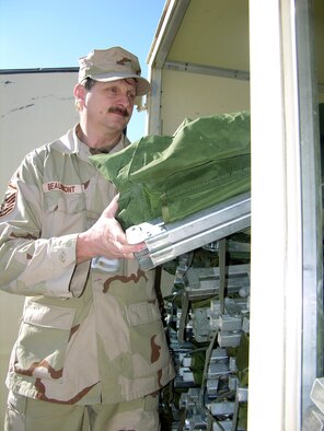 MANAS AIR BASE, Kyrgyzstan -- Master Sgt. Davey Beaumont puts cots away after more than 1,200 of them were setup for transient troops during a weeklong surge.  Sergeant Beaumont is assigned to the 376th Expeditionary Services Squadron here.  (Digitally altered U.S. Air Force photo by Staff Sgt. J. Russell Martin)