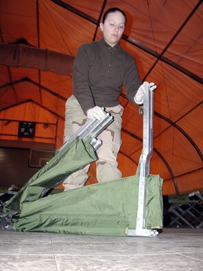 MANAS AIR BASE, Kyrgyzstan -- Senior Airman Melissa Cruz breaks down a cot after more than 150 transient Soldiers bunked in the gym for two nights.  Airman Cruz is assigned to the 376th Expeditionary Services Squadron here.  (U.S. Air Force photo by Staff Sgt. J. Russell Martin) 