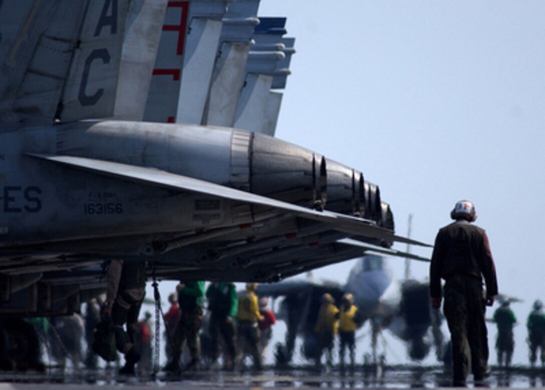 A plane captain walks behind the after burners of F/A-18 Hornet aircraft prior to flight operations aboard the aircraft carrier USS Harry S. Truman (CVN 75) as the ship steams in the Persian Gulf on Feb. 24, 2005. Aircraft from Carrier Air Wing 3 embarked on Truman are providing close air support and conducting Intelligence, Surveillance and Reconnaissance missions in ongoing operations. 