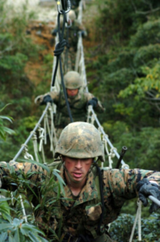 U.S. Marines cross a three-strand bridge through the treetop canopy at the beginning of an endurance course at the Jungle Warfare Training Center on Camp Gonslaves, Okinawa, Japan, on Feb. 25, 2005. The course is a 3.4-mile obstacle course and is part of a weeklong jungle skills training class. 