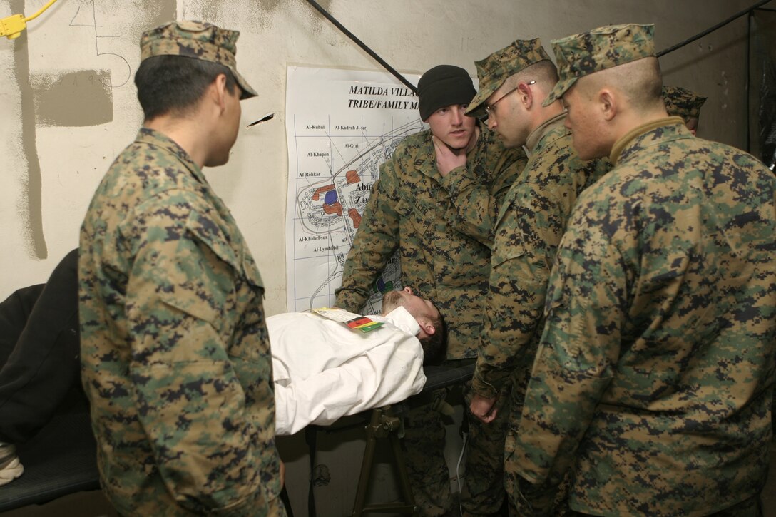 : MARCH AIR RESERVE BASE, Calif. - Navy Seaman Micah L. Selcer, Headquarters and Service Company, 1st Battalion, 6th Marine Regiment corpsman, shows fellow docs how to treat a gunshot wound to the neck on an Iraqi doctor role player.  The unit practiced conducting security and stabilization operations aboard Matilda Village here to prepare for a deployment to Iraq in March.