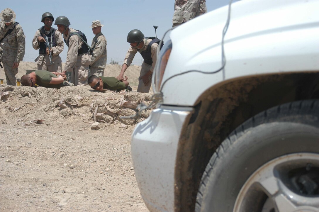 CAMP ALI Ar Ramadi, Iraq - Members of the Iraqi Security Forces hold down Lance Cpl.s Steven A. Anderson and Diego A. Camargo, both rifleman and instructors with the Combined Action Platoon, Company B, 1st Battalion, 5th Marine Regiment, during training session at a mock vehicle checkpoint here. Anderson, 18, of Vacaville, Calif., Camargo, 25, of Dallas and their fellow platoon members are responsible for training new members of the Iraqi Security during the infantry battalion's deployment in support of Operation Iraqi Freedom.   Photo by: Cpl. Tom Sloan