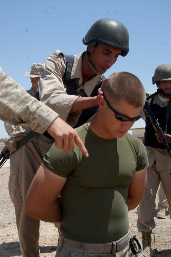 CAMP ALI Ar Ramadi, Iraq - A Marine with the Combined Action Platoon, Company B, 1st Battalion, 5th Marine Regiment, instructs A member of the Iraqi Security Forces on how to detain and search Lance Cpl. Steven A. Anderson during a training mission a mock vehicle checkpoint here. The 18-year-old rifleman from Vacaville, Calif., and his fellow Marines with the platoon are responsible for training new members of the Iraqi Security Forces during the infantry battalion's deployment in support of Operation Iraqi Freedom.   Photo by: Cpl. Tom Sloan