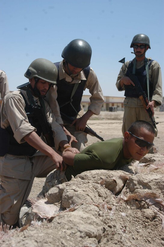 CAMP ALI Ar Ramadi, Iraq (May 31, 2005) - Iraqi Police Officers detain Lance Cpl. Diego A. Camargo, a rifleman and instructor with the Combined Action Platoon, Company B, 1st Battalion, 5th Marine Regiment, at a mock vehicle checkpoint during a training session here. The 25-year-old from Dallas and his fellow Marines with the platoon are responsible for training new members of the Iraqi Security Forces - police and New Iraqi Army Soldiers - during the infantry battalion's deployment in support of Operation Iraqi Freedom. The platoon has trained 300 soldiers and 300 police officers since assuming the training role two months ago. Photo by: Cpl. Tom Sloan