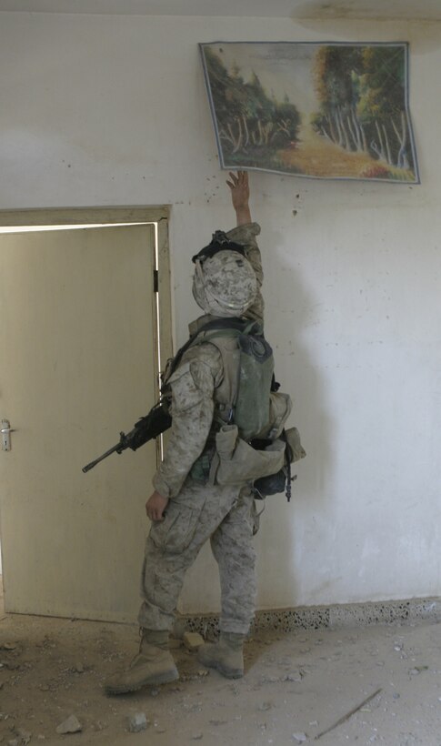 FALLUJAH, Iraq - Lance Cpl. Joseph A. Wheeler, an M249 squad automatic gunner with 3rd Platoon, Company B, 1st Battalion, 6th Marine Regiment, searches behind a painting inside a ruined home here during 'Operation Hard Knock.'  The 21-year-old Bumpass, Va. native's unit worked alongside Iraqi Security Forces to search through every house and field in a sector of Fallujah, confiscate numerous weapons and explosive materials, and detain four known insurgent supporters.
