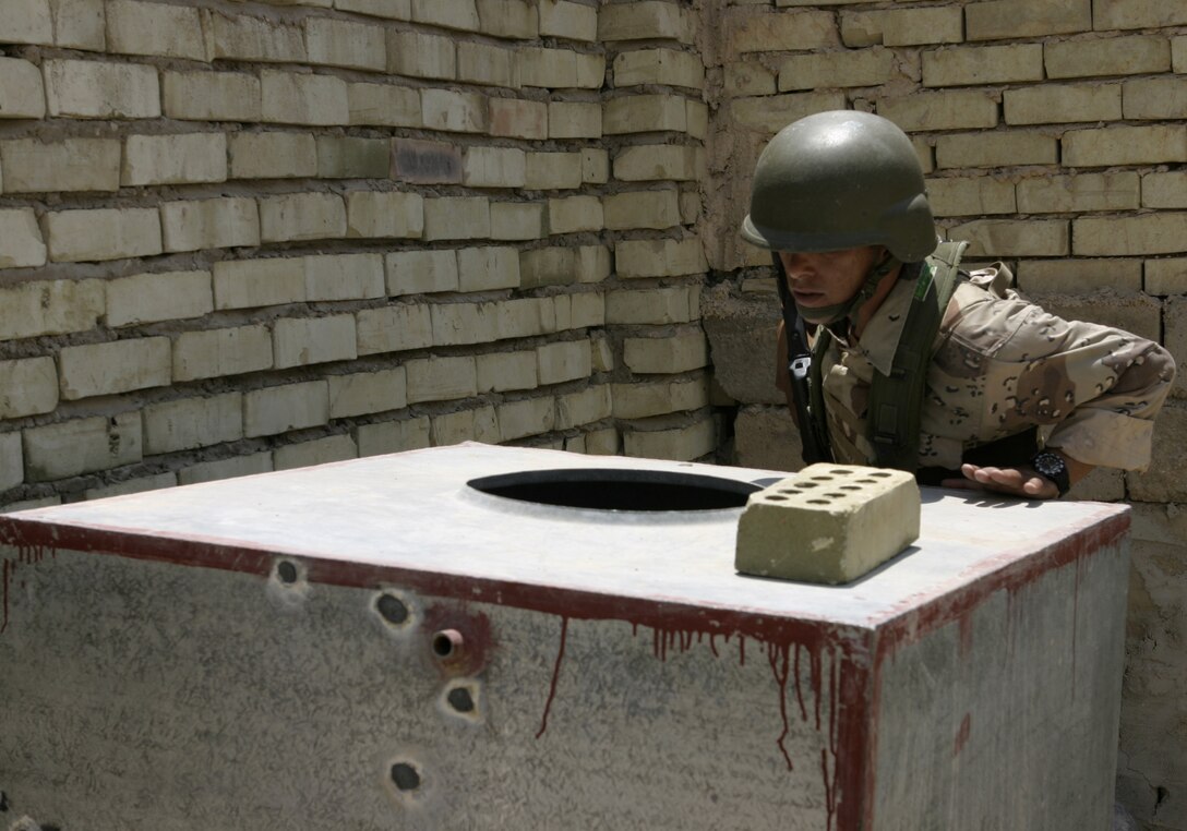 FALLUJAH, Iraq - An Iraqi soldier searches through an empty water tank in an abandoned house here June 1 during 'Operation Hard Knock.'  The soldiers worked alongside Marines from Company B, 1st Battalion, 6th Marine Regiment to search through every house and field in a sector of Fallujah, confiscate numerous weapons and explosive materials, and detain four known insurgent supporters.