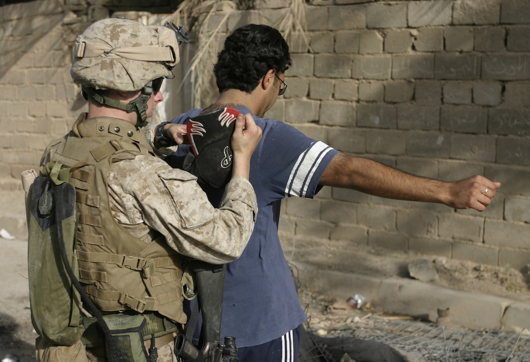 FALLUJAH, Iraq - A Marine with Company B, 1st Battalion, 6th Marine Regiment searches a detainee for weapons here June 1 during 'Operation Hard Knock.'   U.S. Marines worked alongside Iraqi soldiers to search through every house and field in a sector of Fallujah, confiscate numerous weapons and explosive materials, and detain four known insurgent supporters.