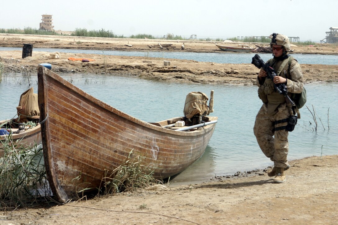 THAR THAR REGION, Iraq - Lance Cpl. Anthony Lazzarotto, a rifleman with 2nd Squad, 2nd Platoon, Company B, 1st Battalion, 6th Marine Regiment, patrols alongside the shorelines of the Thar Thar Lake June 19 as he assists his unit in looking for hidden weapons and explosives.  Lazzarotto's unit is currently conducting security and stability operations in Iraq's Al Anbar province.