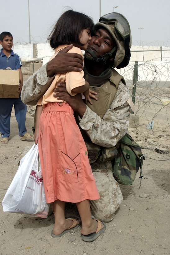 FALLUJAH, Iraq - Sgt. Kent D. Padmore, guard chief for Fallujah's Civil-Military Operations Center's Entry Control Point-7, receives a kiss from an Iraqi girl outside Fallujah's Civil-Military Operations Center Aug. 11.  U.S. Marines and Iraqi police distribute clothes and toys to local children outside the center every week, while local and military officials inside issue compensation payments and brainstorm ideas to rebuild the city's infrastructure.