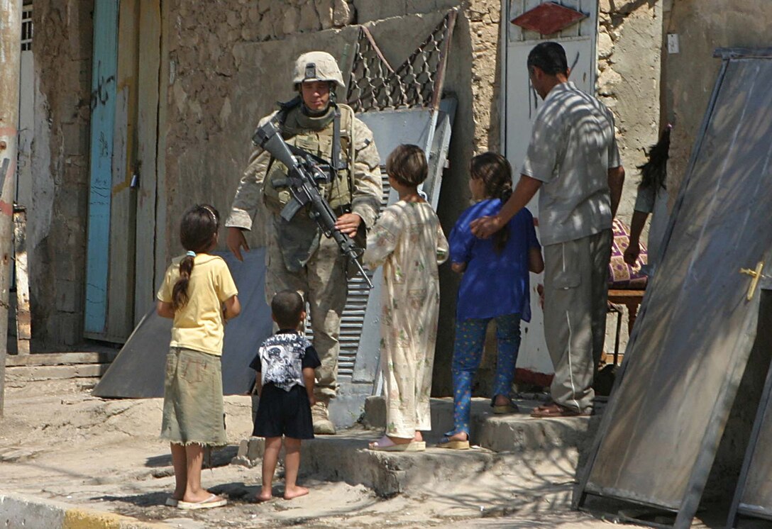 HIT, Iraq (Sept. 15, 2005)  -Lance Cpl. Randy B. Lake, a Battle Ground, Wash. native and radio operator with India Company, 3rd Battalion, 1st Marine Regiment talks to some children during a patrol here Sept. 15. Lake returns to Iraq to support the Global War on Terrorism. (Official Marine Corps photo by Cpl. Adam C. Schnell)