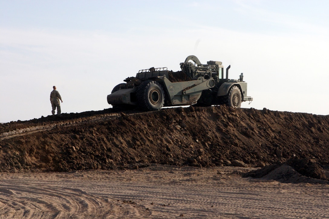 CAMP HABBANIYAH, Iraq - A Marine with the Heavy Equipment Platoon, 8th Engineer Support Battalion, observes as a scraper moves up a newly built berm to lay another layer of dirt. The berms on the two 50 meter ranges and three 300 meter ranges that they are building must be a minimum of 15 feet high.