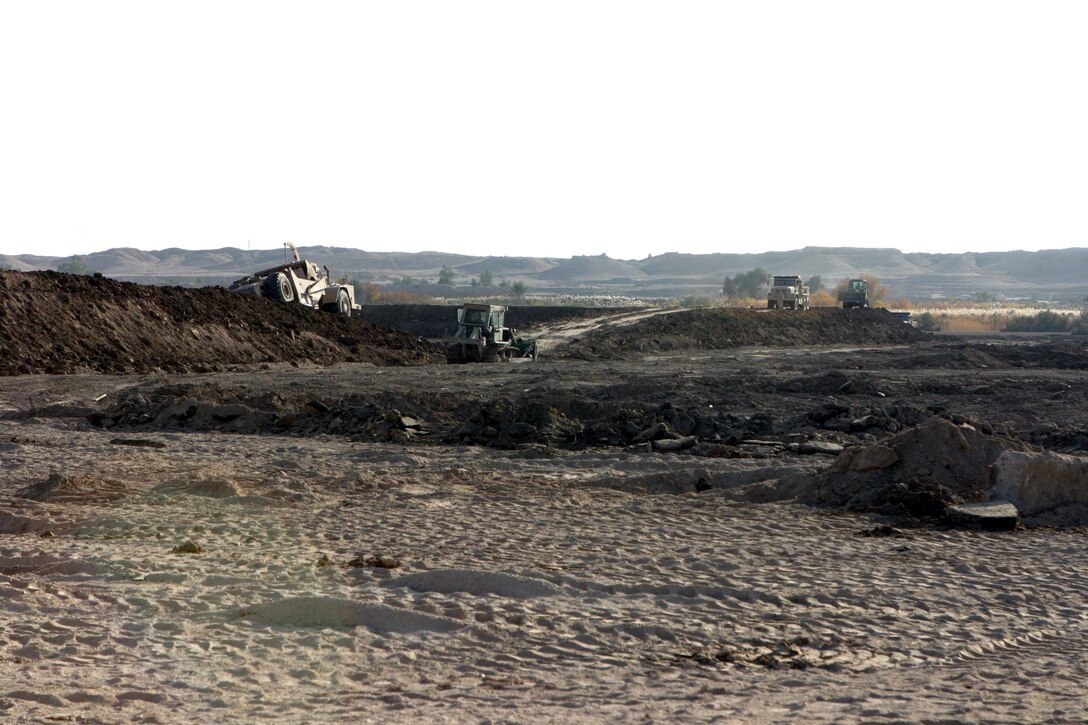 CAMP HABBANIYAH, Iraq - Scrapers, bull dozers and dump trucks from Heavy Equipment Platoon, 8th Engineer Support Battalion, are used to build berms for two 50 meter ranges and three 300 meter ranges here. Each berm must reach a minimum of 15 feet in height.