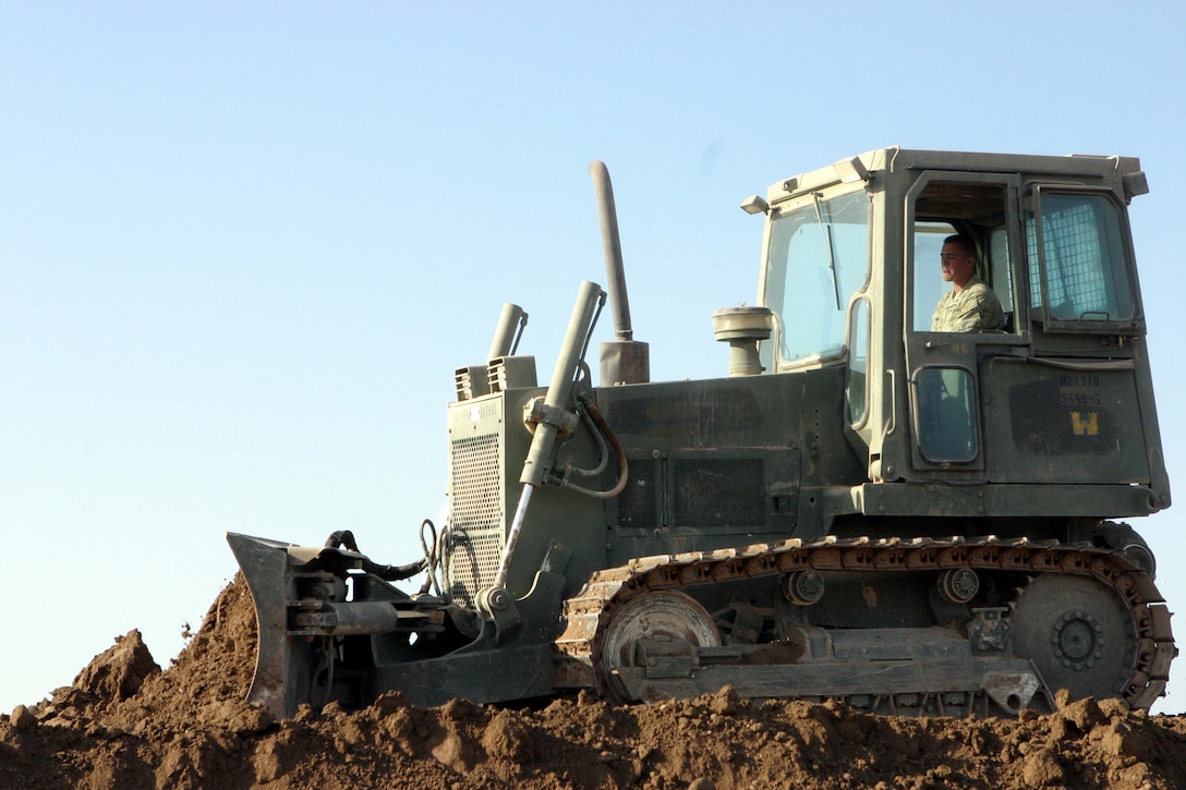 CAMP HABBANIYAH, Iraq - A bull dozer operator with Heavy Equipment Platoon, 8th Engineer Support Battalion, evens out layers of dirt placed along a new berm by scrapers. Each berm must be a minimum of 15 feet in height.