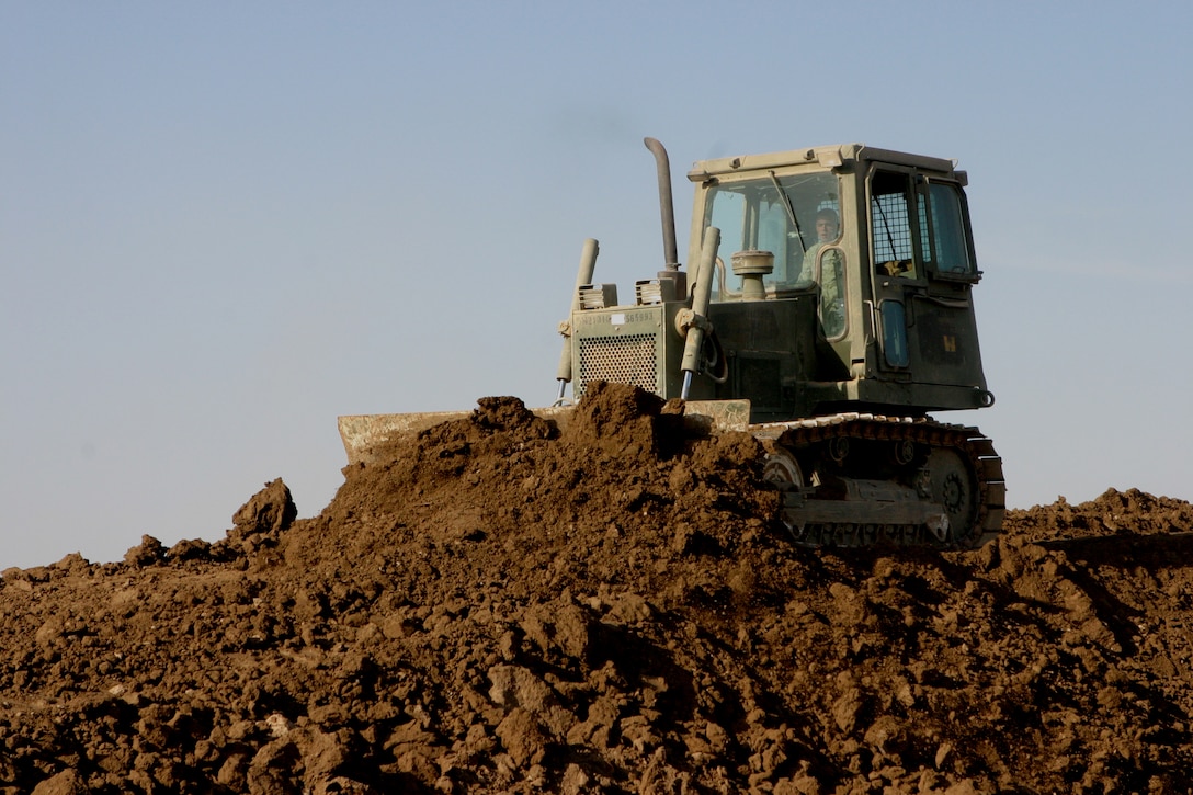 CAMP HABBANIYAH, Iraq - A bull dozer operator with Heavy Equipment Platoon, 8th Engineer Support Battalion, evens out layers of dirt placed along a new berm by scrapers. Each berm must be a minimum of 15 feet in height.