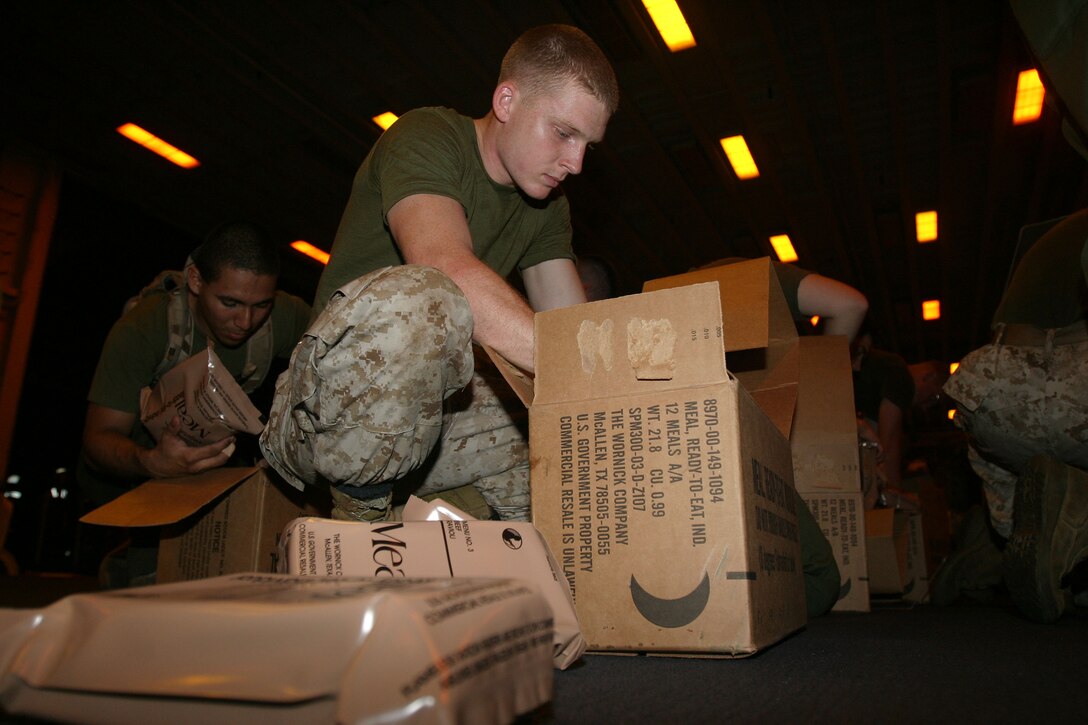 Corporal Mathew R. Loper, 20, a radio operator with the 15th Marine Expeditionary Unit (Special Operations Capable) prepares hundreds of cases of Meals Ready to Eat to hand out to victims of the recent tragedy in the Indian Ocean.