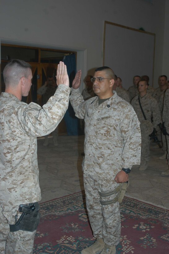CAMP HURRICANE POINT Ar Ramadi, Iraq (May 1, 2005) - With his right hand raised, Master Sgt. Roland Salinas, the operations chief with Head Quarters and Service Company, 1st Battalion, 5th Marine Regiment, swears to support and defend the Constitution of the United States of America while being promoted to the rank of master gunnery sergeant by his commanding officer, Lt. Col. Eric M. Smith, during a ceremony here. The 42-year-old from San Antonio, Texas, reached the final rung on the Marine Corps' ladder of success for enlisted personnel after serving more than 24 years. Salinas reenlisted in Iraq and has three years left on his twilight contract. Photo by Cpl. Tom Sloan
