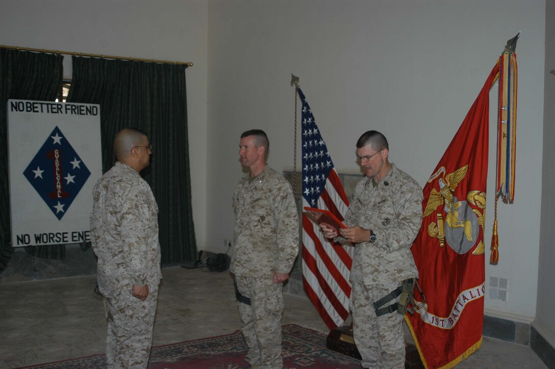 CAMP HURRICANE POINT Ar Ramadi, Iraq (May 1, 2005) -Sergeant Major Charles T. Blumenburg, battalion sergeant major, 1st Battalion, 5th Marine Regiment, stands to the left of the infantry battalion's commanding officer, Lt. Col. Eric M. Smith, and reads Master Sgt. Roland Salinas' promotion warrant during a ceremony here. The 42-year-old operations chief with Headquarters and Service Company and San Antonio, Texas, native reached the final rung on the Marine Corps' ladder of success for enlisted personnel when he was promoted to the rank of master gunnery sergeant after serving more than 24 years. Salinas reenlisted in Iraq and has three years left on his twilight contract. Photo by Cpl. Tom Sloan