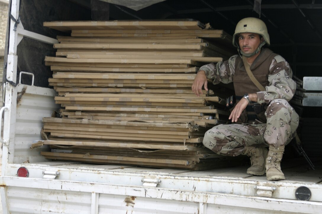 FALLUJAH, Iraq - An Iraqi soldier crouches inside his truck and prepares to begin offloading blackboards here May 2.  Iraqi Security Forces and Marine forces here visited local schools to distribute blackboards, school desks, and writing supplies as part of the ongoing joint civil-military mission, "Operation Blackboard."
