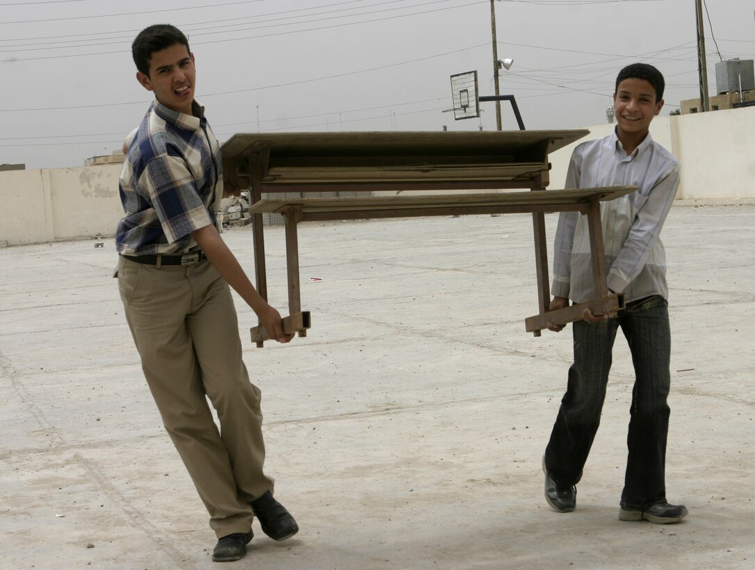 FALLUJAH, Iraq - Two Iraqi schoolchildren carry a new desk that local soldiers gave them into their school here May 2.  Iraqi Security Forces and Marine forces here visited local schools to distribute blackboards, school desks, and writing supplies as part of the ongoing joint civil-military mission, "Operation Blackboard."