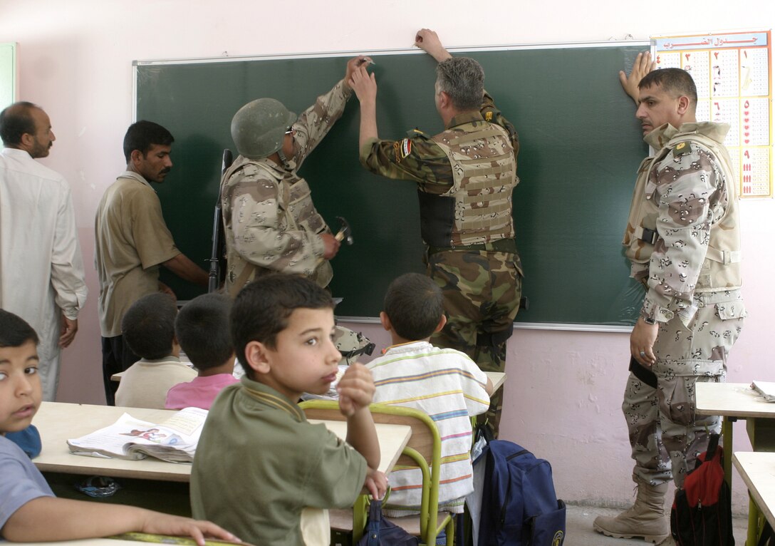 FALLUJAH, Iraq - From right to left, back: Iraqi Maj. Muhammad-Hasan Hasan Fuaad, executive officer for 1st Battalion, 2nd Brigade, Iraqi Security Forces, Iraqi Maj. Laith Jabbar Al Tememey,  company commander for 1st Company, 1st Battalion, 2nd Brigade, an Iraqi soldier, and two teachers hang up a new blackboard inside a school classroom here May 2.  Iraqi Security Forces and Marine forces here visited local schools to distribute blackboards, school desks, and writing supplies as part of the ongoing joint civil-military mission, "Operation Blackboard."