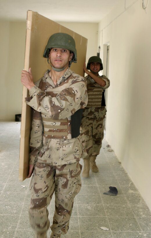 FALLUJAH, Iraq - Iraqi soldiers from 1st Battalion, 2nd Brigade carry a new chalkboard through a school here May 2.  Iraqi Security Forces and Marine forces here visited local schools to distribute blackboards, school desks, and writing supplies as part of the ongoing joint civil-military mission, "Operation Blackboard."