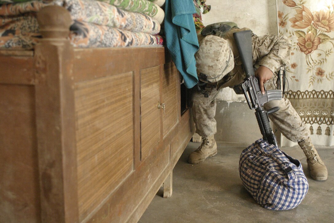 ASRAGIYAH, Iraq - Pfc. Julio Hernandez, a rifleman with 4th Platoon, Company C, 1st Battalion, 6th Marine Regiment, searches through furniture inside a house here June 2 during 'Operation Hard Knock.'  Company C personnel worked alongside Iraqi soldiers to sweep through the farming community outside Fallujah and confiscate several AK-47 assault rifles.