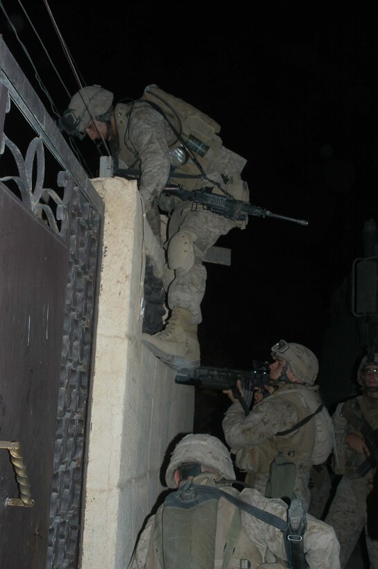 AR RAMADI Iraq (July 2, 2005)  --Lance Cpl. Manuel Valle Jr., a rifleman and team leader with 2nd Squad, 1st Platoon, Company A, 1st Battalion, 5th Marine Regiment, scales a wall to gain entrance to a building during a mission in the city here early July 2. The 22-year-old from Parlier, Calif., and fellow Company A Marines conducted a raid in the Al Anbar capital between midnight and 5 a.m. and apprehended three insurgents. Photo by: Cpl. Tom Sloan
