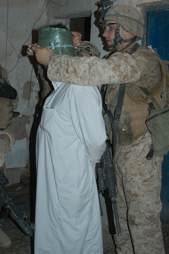 AR RAMADI Iraq (July 2, 2005)  --Lance Cpl. Mark T. McAuliffe, an assault man with 2nd Squad, 1st Platoon, Company A, 1st Battalion, 5th Marine Regiment, blindfolds an insurgent during a mission in the city here July 2. The 23-year-old from Seattle and fellow Company A Marines conducted a raid in the Al Anbar capital between midnight and 5 a.m. and apprehended three insurgents. Photo by: Cpl. Tom Sloan